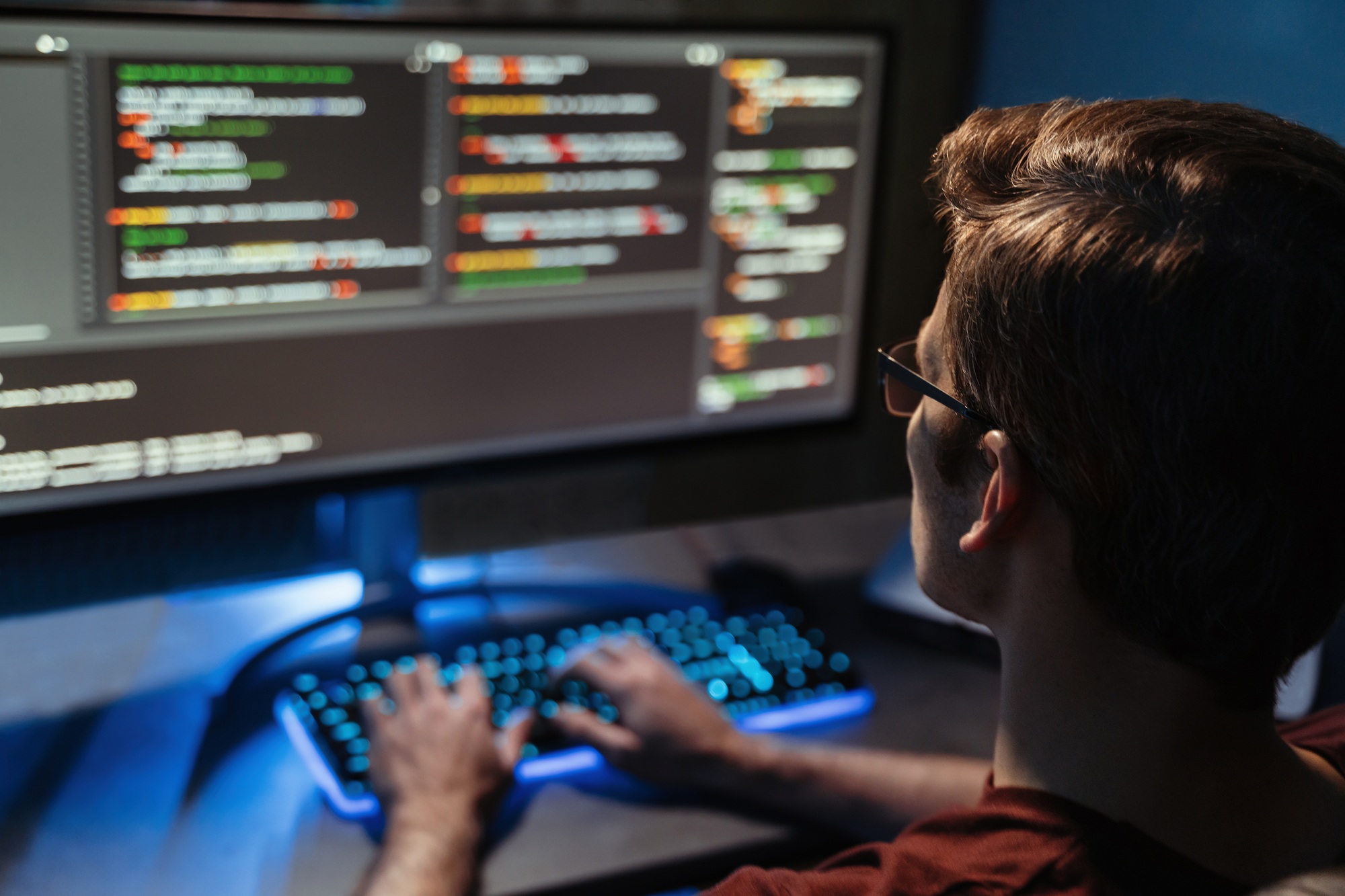 Back view of man coding for cyber security, programming and working from home at pc screen