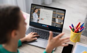 Cropped teenage girl student studies remotely, watching lesson with millennial teacher at home