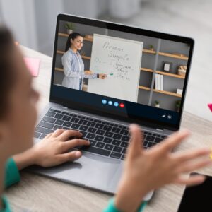 Cropped teenage girl student studies remotely, watching lesson with millennial teacher at home