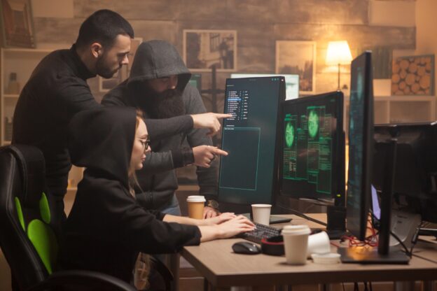 Team of hackers pointing on computer screen